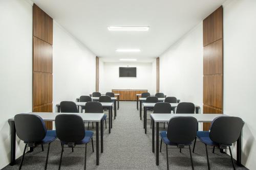 a conference room with tables and chairs and a screen at Sumaré Park Hotel in Sumaré