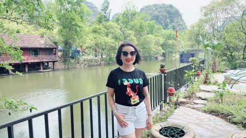 a woman standing on a fence near a river at Trang an green river homestay in Ninh Binh