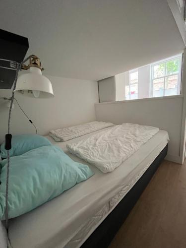 1 dormitorio con 2 camas sin hacer y una lámpara en Appartementen het Centrum, en Domburg