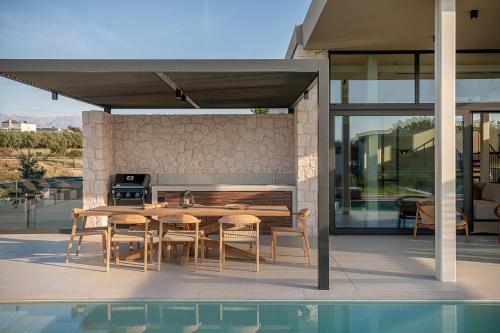 patio con mesa y sillas y cocina en Pnoe Villas - Seafront Experience en Tavronitis