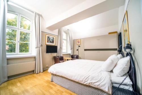 a bedroom with a white bed and two windows at Långholmen Hotell in Stockholm