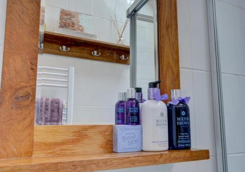 a shelf with bottles of soap and a mirror at The Den in Lynmouth