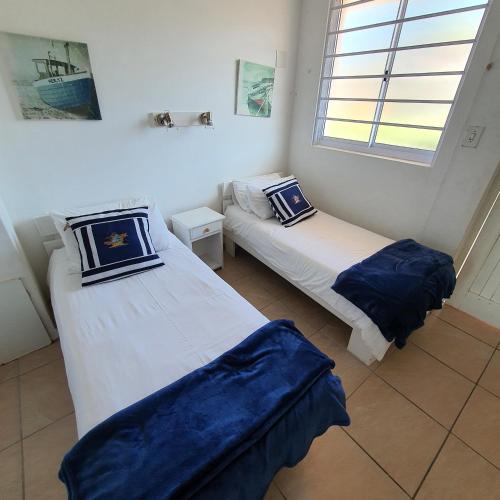 two beds sitting in a room with a window at Driftsands Sea View Flats in Uvongo Beach