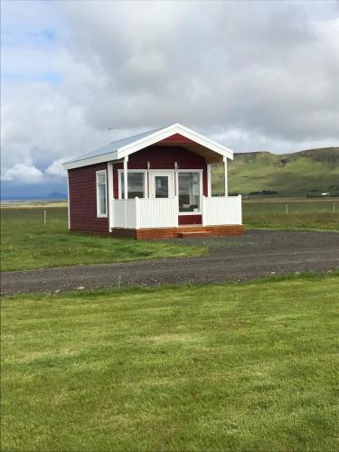 a small red and white house in a field at Hekla Adventures in Hvolsvöllur