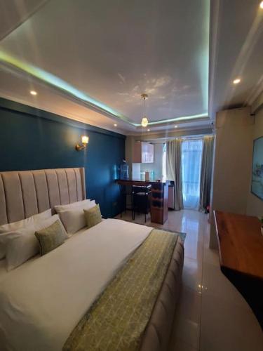 a bedroom with a large white bed and a desk at Cozy Studio Stay Kilimani Valley Acarde Area in Nairobi