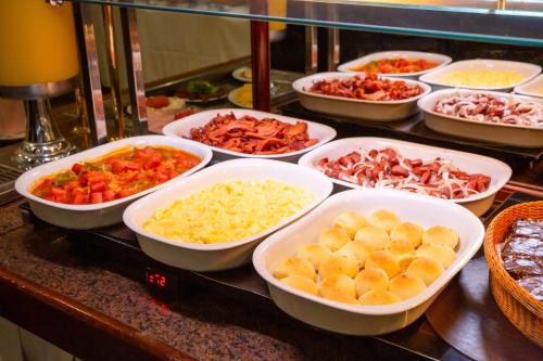 a buffet filled with bowls of different types of food at Rio Aeroporto Hotel Galeão in Rio de Janeiro