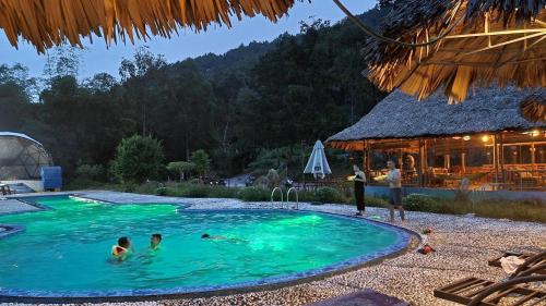 a group of people in a swimming pool at a resort at Woodstock Jungle Camp in Cat Ba