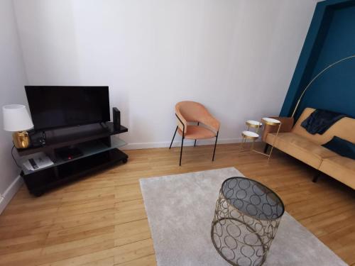 ein Wohnzimmer mit einem Sofa und einem TV in der Unterkunft Magnifique Appartement Esprit Art Déco in Romans-sur-Isère
