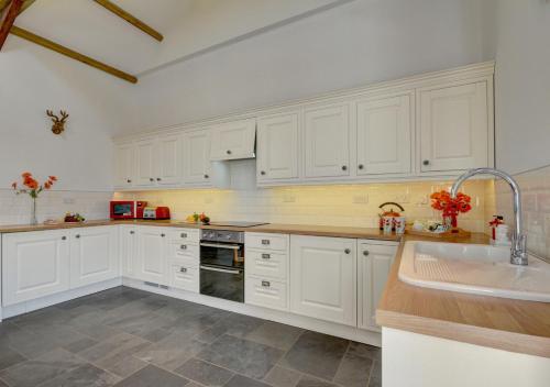 a white kitchen with white cabinets and a sink at The Granary Muddiford in Shirwell