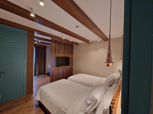 a bedroom with two beds and a flat screen tv at Palorto Traditional Hotel in Gjirokastër