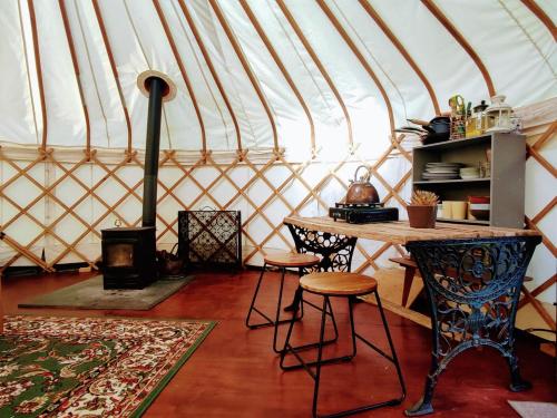 GraffhamにあるBeautiful Yurt with stunning South Downs viewsのパオのテーブルとスツール付きの部屋