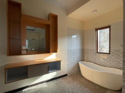 a bathroom with a tub and a sink and a mirror at Semabu Hills Hotel Nusa Penida in Nusa Penida