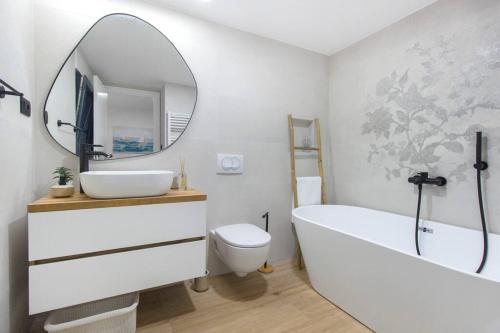a bathroom with a tub and a sink and a mirror at Seafront villa with roofpool, perfect getaway in Vinišće