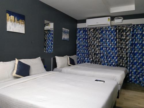 2 Betten in einem Zimmer mit blauen und weißen Vorhängen in der Unterkunft Silver Cloud Hotel Sholinganallur in Chennai