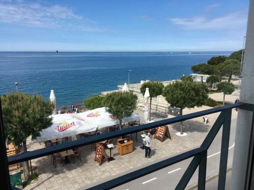 a person standing on a sidewalk next to the ocean at Sunny Beach Apartment by Locap Group in Piran