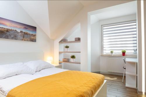 a white bedroom with a yellow bed and a window at Apartament Baltic C21 in Darłowo
