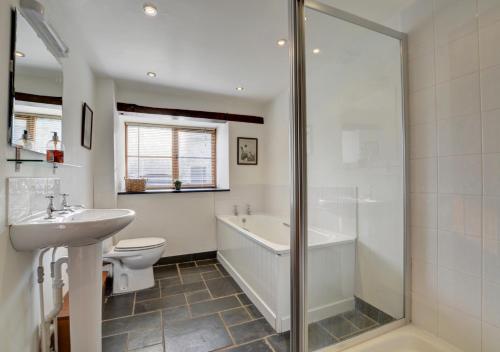 a bathroom with a tub and a toilet and a sink at Hawthorn Cottage in Barbrook