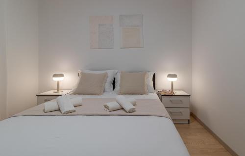 een slaapkamer met een groot wit bed met 2 lampen bij Apartman Marino in Trogir