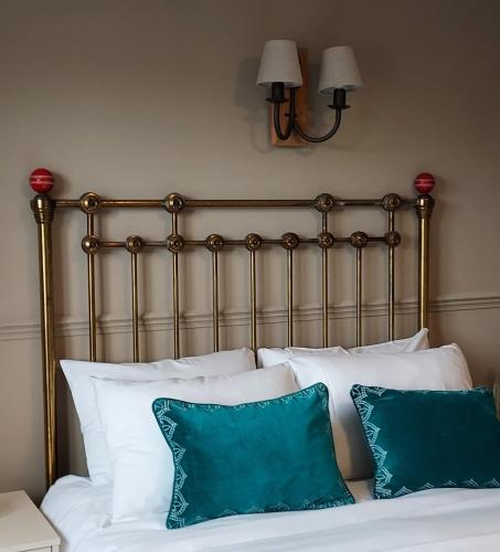 a bed with white pillows and a metal headboard at The Cricketers Inn in Petersfield