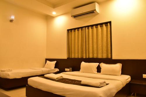 een hotelkamer met 2 bedden en een televisie bij Hotel Dhantara in Shirdi