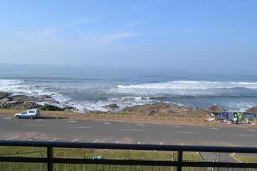 a car driving down a road next to the ocean at Driftsands Sea View Flats in Uvongo Beach