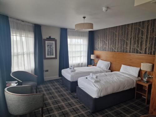 una habitación de hotel con 2 camas y una silla en The Queen Hotel Wetherspoon en Aldershot