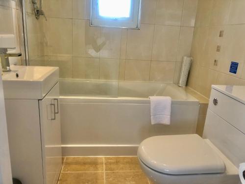 a bathroom with a toilet and a tub and a sink at The Old Quay House in Hayle