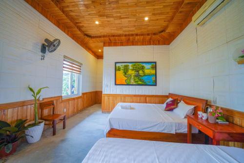 a bedroom with two beds and a table and a window at Phong Nha Dawn Home in Phong Nha