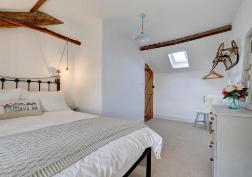 a white bedroom with a bed and a chair at July Cottage in West Down