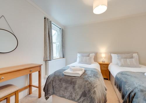 1 dormitorio con 2 camas, escritorio y ventana en Karrys, en Lynmouth