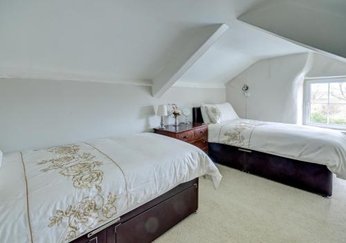 a white bedroom with two beds and a window at Laurel Cottage in Parracombe