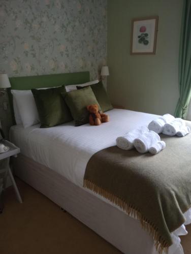 Una cama con toallas y un osito de peluche. en Smiddy House, en Spean Bridge