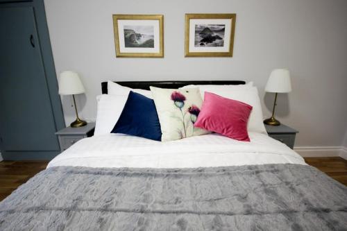 a bedroom with a white bed with colorful pillows at Atlantic Way Cottage in Galway