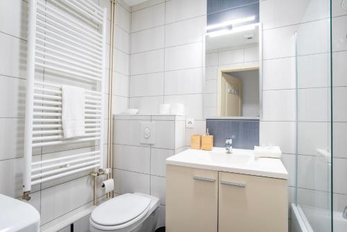 a white bathroom with a toilet and a sink at Le Fournil - WiFi - Séjournez à proximité de tout in Schiltigheim
