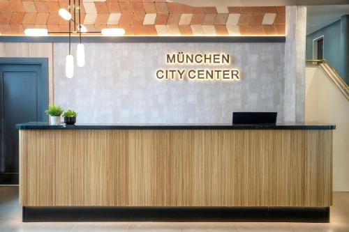 Hotel München City Center affiliated by Meliá في ميونخ: لوبي مكتب مع علامة مركز المدينة ميردفيجي على الحائط
