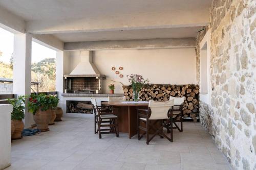 a patio with a table and chairs and a fireplace at Merastri Villa in Zaros