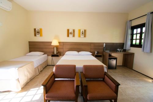 um quarto de hotel com duas camas e duas cadeiras em Hotel Dona Paschoalina em Socorro