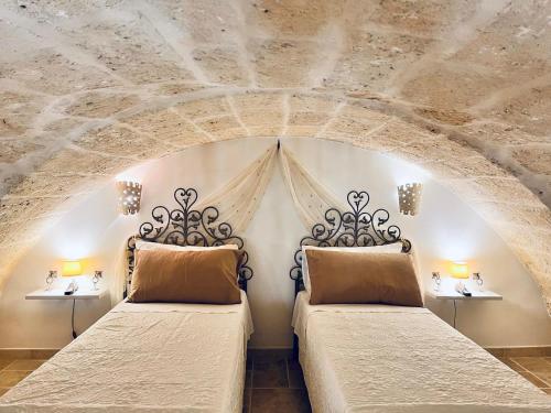 2 letti in una camera da letto con soffitto in pietra di La casa di Jannina a Fasano
