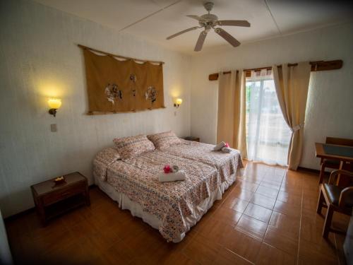 a bedroom with a bed and a ceiling fan at Tupa Hotel in Hanga Roa