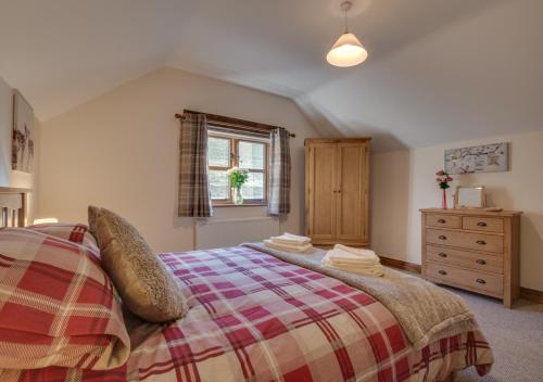 a bedroom with a bed and a dresser and a window at Mill Barn in Bishops Nympton