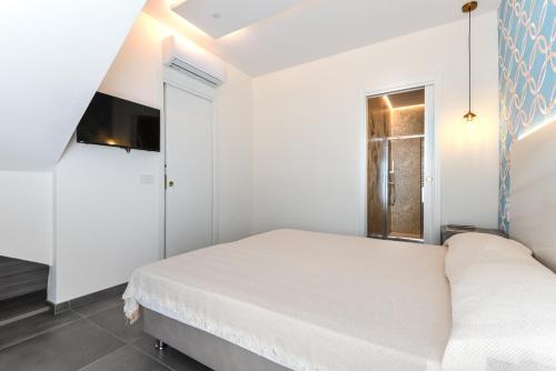 a white bedroom with a bed and a window at Villa Serena vista mare in Lacona