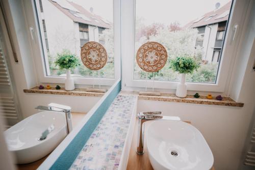 baño con lavabo y aseo y 2 ventanas en SOONWALD Apartment mit Garten & Hot Tube, en Stromberg