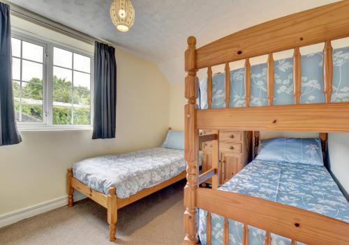 1 Schlafzimmer mit 2 Etagenbetten und 2 Fenstern in der Unterkunft Pusehill Cottage in Westward Ho