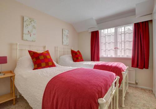 two beds in a room with red curtains at Dune View Instow in Instow
