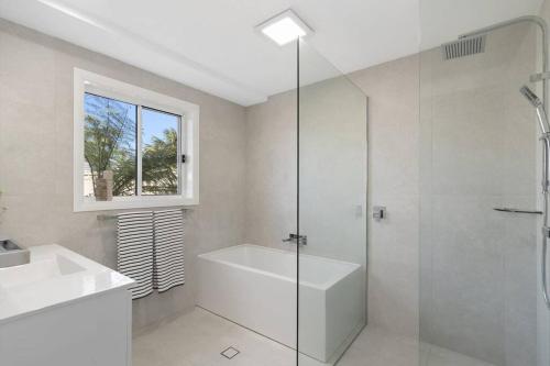 a white bathroom with a shower and a sink at Luxury in dress circle location 