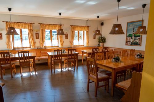 a restaurant with wooden tables and chairs and windows at Pension U Kostela in Frymburk