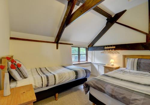 two beds in a room with wooden beams at Button Stable in Bratton Fleming