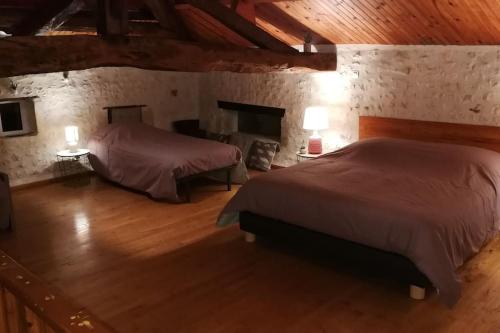 a bedroom with two beds and two lamps in a building at Maison charentaise à la campagne in Bécheresse