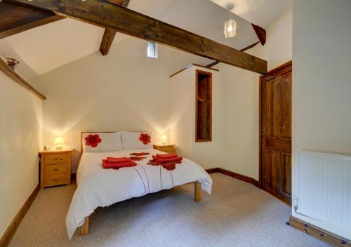 a bedroom with a large white bed with red towels on it at Button Barn in Bratton Fleming
