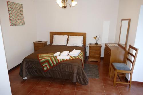 a bedroom with a bed with a table and a chair at Casa nos Penedos in Arcos de Valdevez